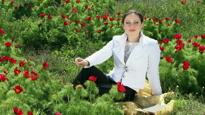 A beautiful girl is sitting on the field of pions. And fun laughs.