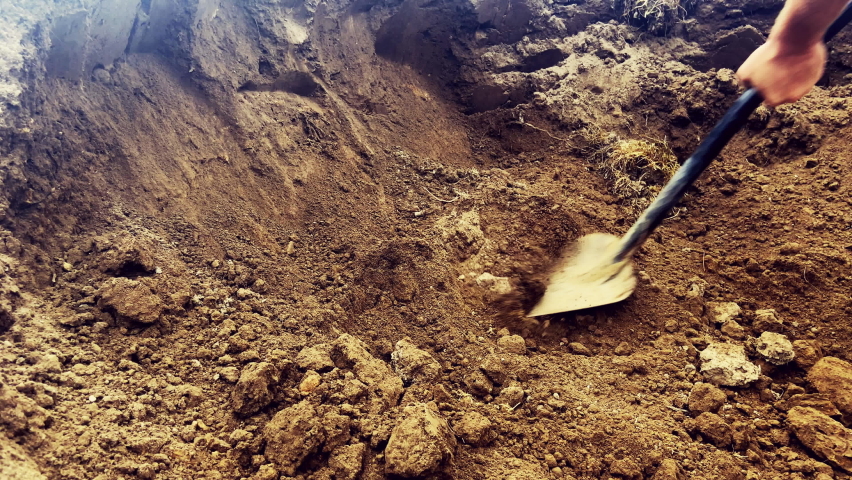 Digging soil with shovel. Worker digs the ground with a shovel. Digging soil in the garden. Shovel Digs a Underground Hole with a Shovel at the construction site. Royalty-Free Stock Footage #1096007107