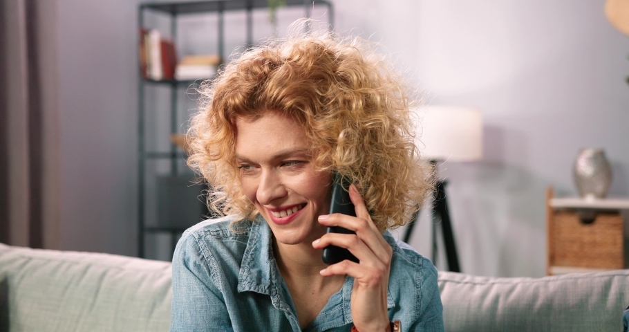 Happy beautiful blonde curly multiracial woman involved in pleasant smartphone call conversation with friends while sharing and discussing life news. Smiling female client calling operator