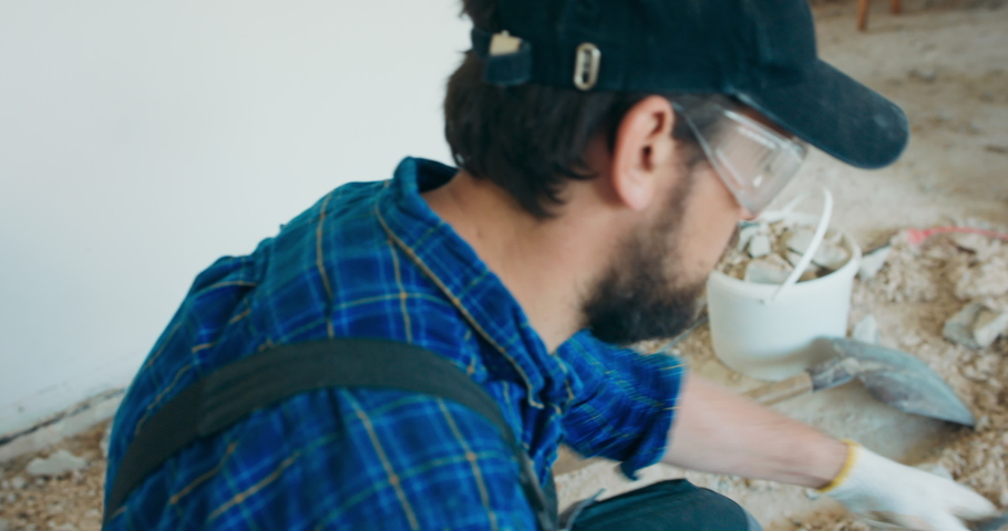 Builder prepares hand hammer to demolish wall, applies drill, renovates apartment.