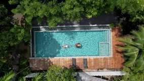 aerial drone view of swimming pool in the jungle of Krabi Thailand, aerial view with a drone above swimming pool in the jungle of Thailand. couple men and woman in pool from above - Powered by Shutterstock - Get 15% off with code: PIKWIZARD15