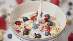 Slow motion milk pouring in bowl of healthy breakfast crunchy Granola Cereals with stawberry , blueberry vegan food, clean eating, dieting concept. - Powered by Shutterstock - Get 15% off with code: PIKWIZARD15