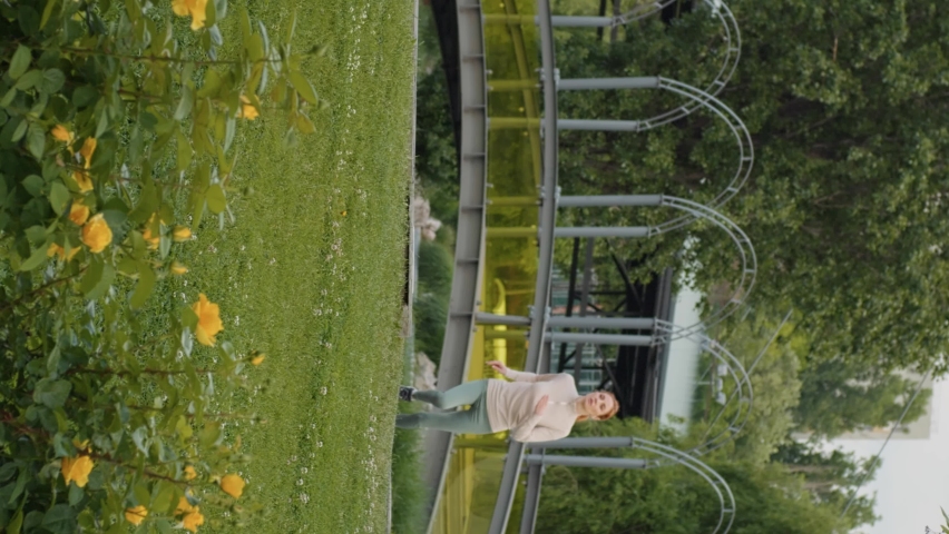 Vertical Screen: Girl making short break to breath while running in the park. Sports activity concept.