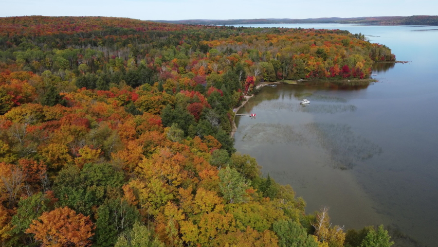 Cinematic drone shot of Rock Lake passing through colorful autumn foliage of Algonquin park, Ontario