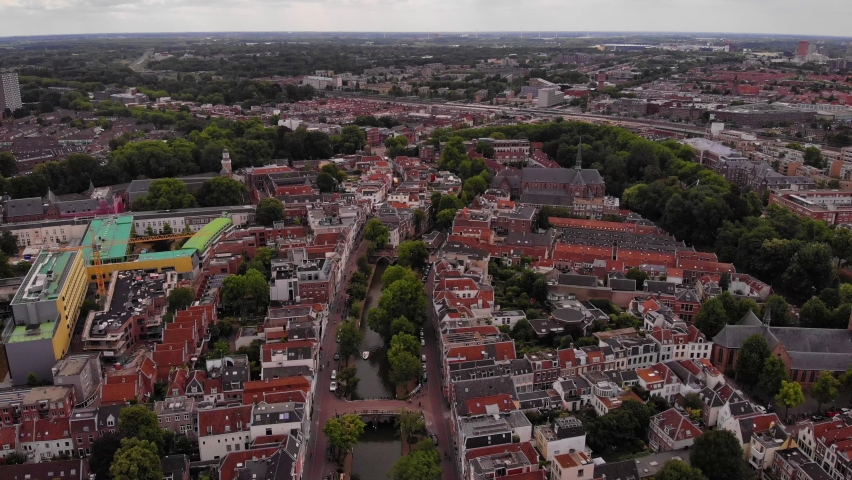 Aerial descending footage of houses in urban borough. Revealing streets and buildings along Oudegracht water canal in city centre. Utrecht, Netherlands