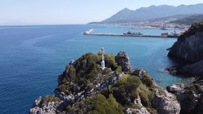 Aerial footage of the coastline of Samos with a lighthouse on a rock and the port of Karlovasi
