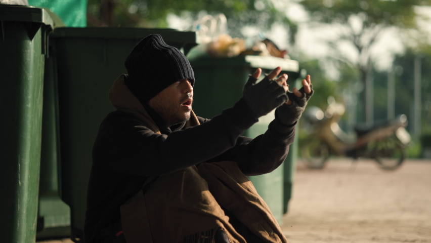 Poor tired stressed depressed hungry homeless man in the shadow city. Homeless man sitting on the street waiting for help food and money from people volunteer foundation donate. Social work immigrant