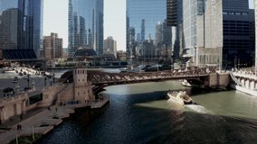 Boat on Chicago River in Chicago, Illinois with drone video following behind and moving up.