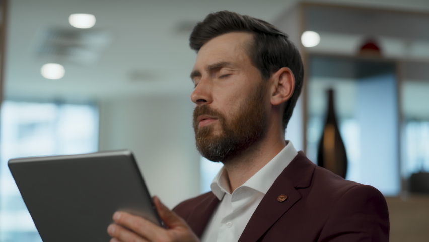 Disappointed employee face palming at lobby closeup. Nervous business man solving problems alone. Worried manager watching tablet screen with sad emotion. Upset ceo thinking about project failure | Shutterstock HD Video #1096037183