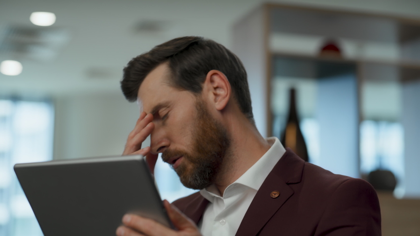 Disappointed employee face palming at lobby closeup. Nervous business man solving problems alone. Worried manager watching tablet screen with sad emotion. Upset ceo thinking about project failure Royalty-Free Stock Footage #1096037183