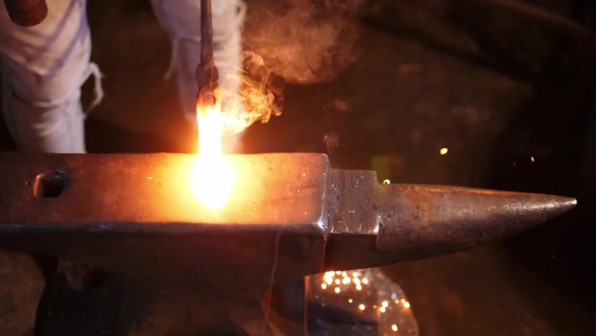 Blacksmith shaping a hot piece of metal on the anvil. Sparks in slow motion. Royalty-Free Stock Footage #1096039791