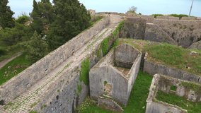 Slowmotion aerial video. A young woman tourist visits the Fortress Spanjola or Spanish fortress in Herceg-Novi. She walks the walls of the fort. Travel to Montenegro