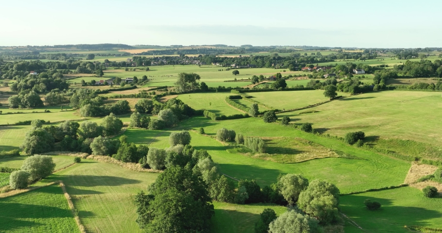 Aerial view flying backwards of valley in hilly countryside with small river Geul and grassland, Geuldal, Mechelen, Zuid Limburg, Netherlands