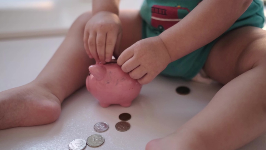 kid puts coins in a piggy bank