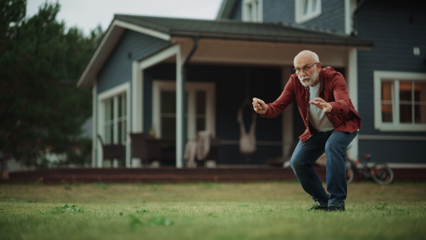 Active Senior Man Enjoying Time Outside with a Pet Dog, Playing with an Energetic White Golden Retriever. Happy Adult Treating a Dog with a Snack During the Training Session on a Front Yard at Home. Royalty-Free Stock Footage #1096061559