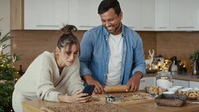 Latin man making gingerbread cookies and caucasian woman using phone next to him. Shot with RED helium camera in 8K.  - Powered by Shutterstock - Get 15% off with code: PIKWIZARD15