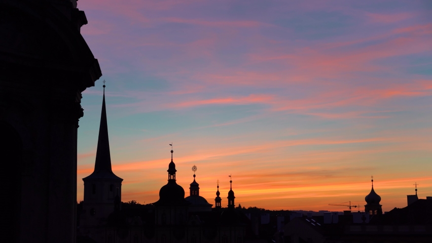 silhouettes of towers on an orange sunrise sky in Prague, Czechia, pan right