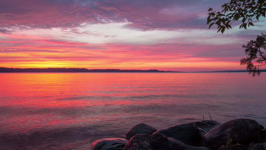 Time-laspe of a blazing red sunset over a lake. Shot onn Torch Lake, Michigan in 4K