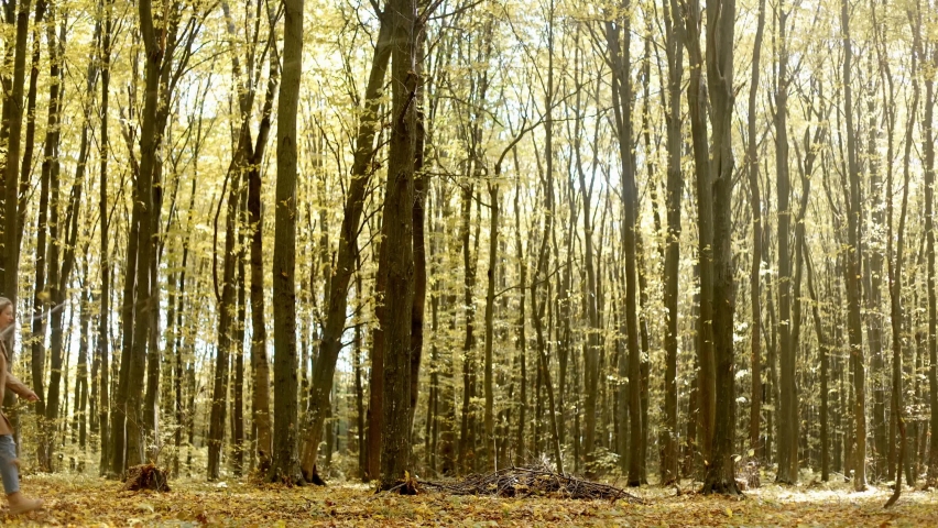 static frame. Side view, long-haired girl woman walking in the autumn forest in the park bouncing and spinning around herself, having fun alone, enjoying life, walking in nature