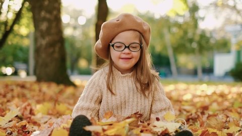 Happy child with down syndrome enjoying in autumn park Stockvideo