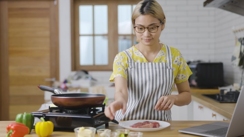 Beautiful young woman  is mixing batter, looking at camera and smiling while baking in kitchen at home ,decorating a cake of chocolate cake,cooking class, culinary, bakery, food and people concept