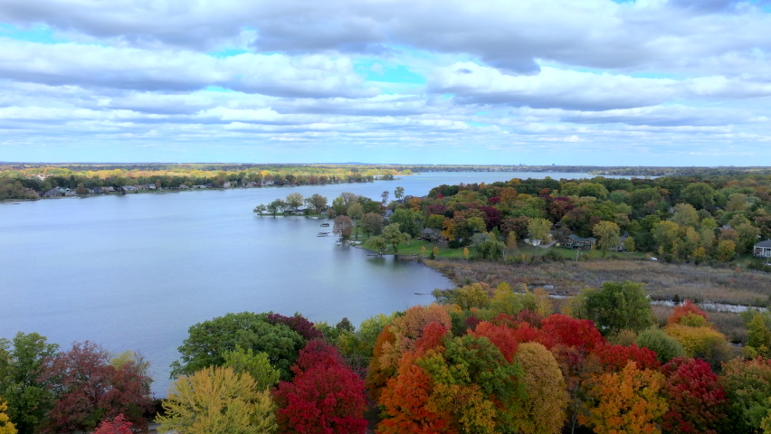 Aerial drone footage of Cass Lake and Orchard Lake in West Bloomfield Michigan during Fall. Beautiful autumn day with colorful leaves all around