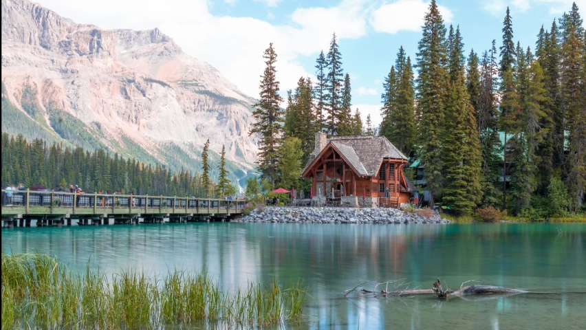 4K time-lapse UHD video of scenery of wooden house with rocky mountains and cloudy blowing reflection on Emerald Lake,a Glacial Lake at Yoho national park in the mountain parks of the Canadian Rocky