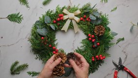 Hands making Christmas wreath. DIY Xmas circular floral decoration. Overhead shot. - Powered by Shutterstock - Get 15% off with code: PIKWIZARD15