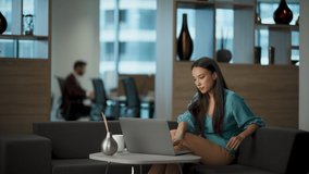 Focused businesswoman using computer in office. Closeup young serious lady looking digital device screen in lounge workplace. Thoughtful asian girl greeting working alone. Busy employee concept