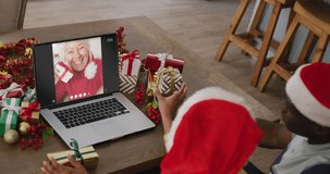 Diverse couple with santa hats having laptop video call with caucasian woman. Christmas, celebration, digital composite video.