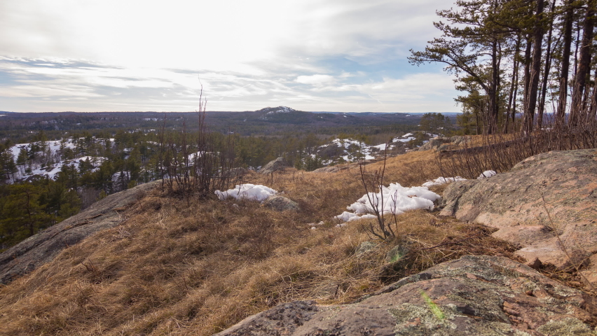Motion time-lapse of clouds moving above forested hillsides in early spring or late winter. Shot near Marquette, Michigan in 4K