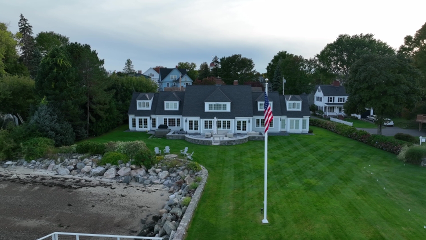 Luxurious mansion with sandy beach view. American flag, USA lifestyle of rich and famous. Aerial view.
