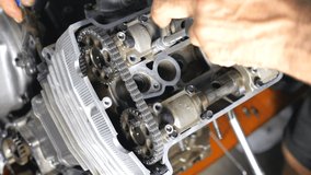 Top view on disassembled motorcycle engine. Professional mechanic repairing motor using tool. Repairer working in garage or workshop. Man engaged servicing cars or motorbikes. Slow motion Close up - Powered by Shutterstock - Get 15% off with code: PIKWIZARD15