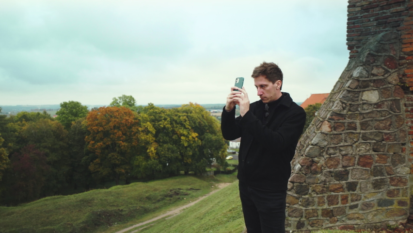 The guy takes pictures on his phone at the walls of the old fortress. Old Castle