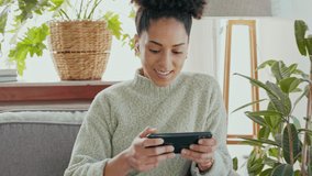 Smartphone, gaming and gamer black woman excited for action, esports or online mobile app use experience on her living room sofa. Winning, happy woman play fast internet video game on her cellphone