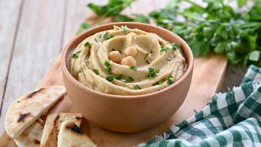 Pouring olive oil into the hummus bowl on wooden table