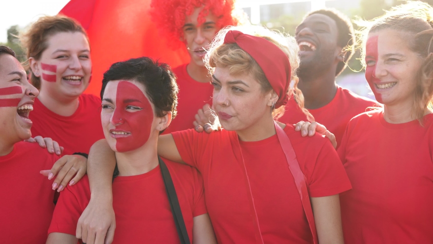 Multiethnic friends football supporter fans watching soccer match at stadium - People with red t-shirts having excited fun on sport world championship event