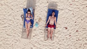 Aerial top view footage view of couple in honeymoon lounging on a sunny day in Maldives island. High quality 4k footage. Drone is going up - Powered by Shutterstock - Get 15% off with code: PIKWIZARD15