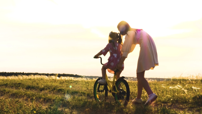 mother teaches little child daughter ride bike park sunset. cycling kid with parent outdoors. happy family. mother daughter play with bicycle nature. happy family concept. chidhood dream. weekend. Royalty-Free Stock Footage #1096118685