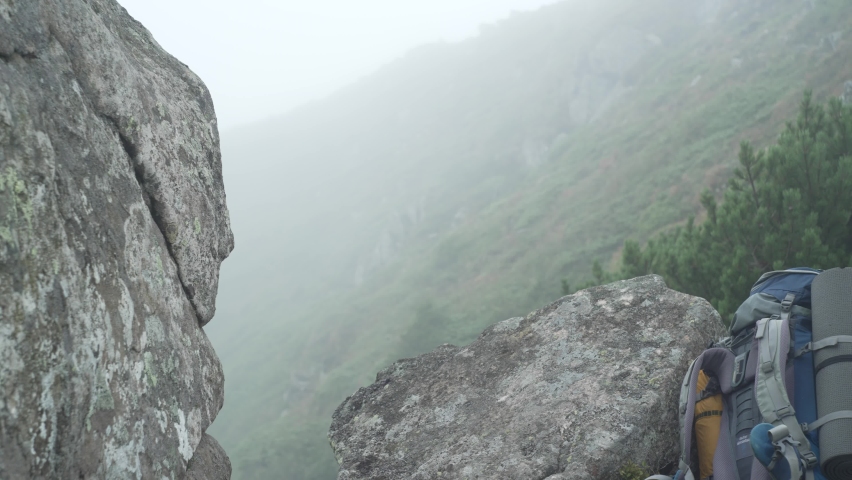 A European man sits on a rock and drinks water. Tortured tourist rests 