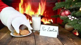 Santa Claus eats oatmeal cookies, drinks a glass of milk and leaves a gift on the background of a Christmas tree, a fireplace and an inscription For Santa - Powered by Shutterstock - Get 15% off with code: PIKWIZARD15