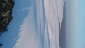 Vertical video. Flight over snow-covered fields. Man travels alone.