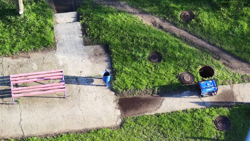 An open sewer well near which there is a gas generator on the grass. The concept of repair and maintenance of inspection and sewer wells. Accident in the water network, industry