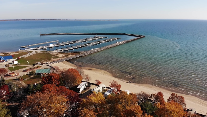 A wide aerial flyover of Harbor Park Marina on Lake Huron in Tawas City, Michigan on a sunny autumn day.