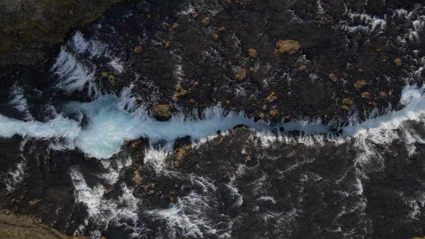 Pedestrian bridge crossing Bruarfoss waterfall, Iceland. Aerial top down sideways directly above