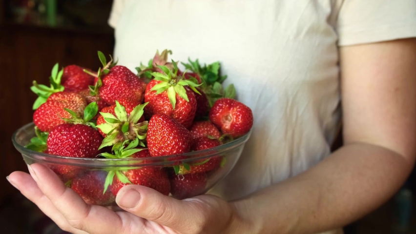 healthy eating, seasonal food. Woman hand holding bowl with ripe red fruit strawberry. Unrecognizable girl ready to eat seasonal summer red berry. Healthy organic dessert, vegan food concept