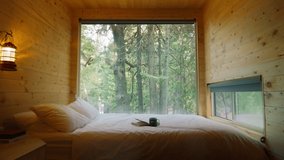 Escape to nature in glamping cabin on weekend day. Bed at green dense forest on motion background. Relaxing at countryside cabin. Opened Pages of Book cinematic dolly slow motion shot on RED camera - Powered by Shutterstock - Get 15% off with code: PIKWIZARD15