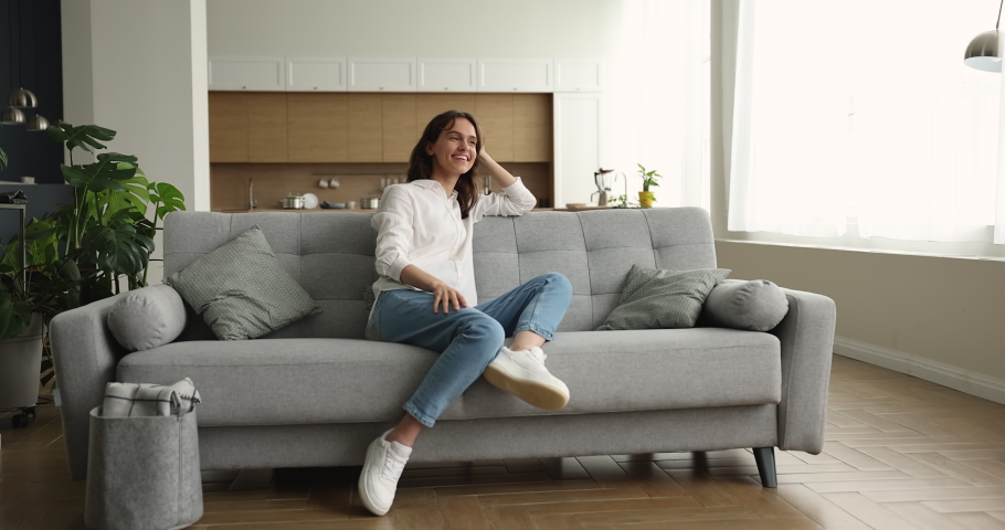 Pensive dreamy woman resting on sofa looking into distance feels happy, enjoy day off, spending carefree weekend alone at modern cozy own or rented dwelling. Tenancy, independence, daydreams concept Royalty-Free Stock Footage #1096165219