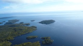 Aerial beautiful drone video of islands and hills with green trees and sea with blue water on a summer cloudy day in Karelia