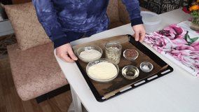 A man demonstrates the ingredients for a multi-grain bread. On a baking sheet are containers with cereals. The camera moves on a slider. - Powered by Shutterstock - Get 15% off with code: PIKWIZARD15